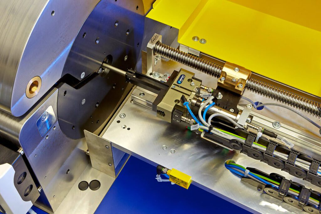 Detailaufnahme einer Fichter-Formtec-Bördelfmaschine: Präzise Mechanik mit Kabeln, Sensorik und Schutzabdeckung in Gelb und Blau