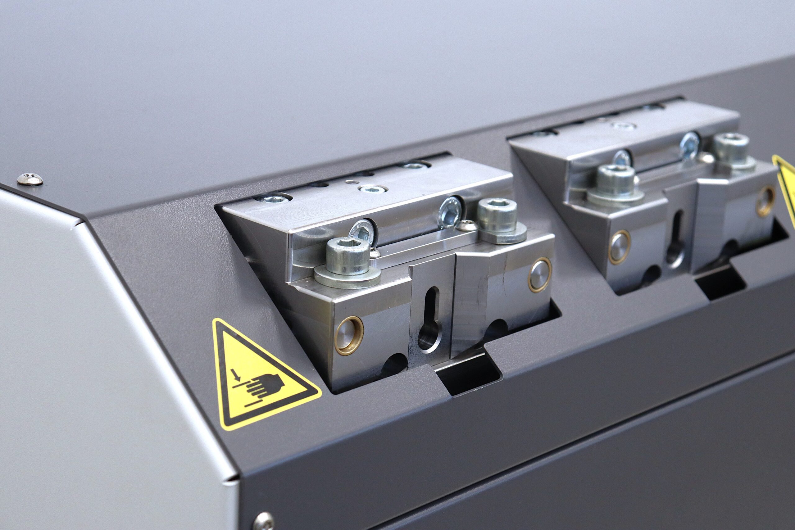 Detailaufnahme der Spannvorrichtung einer Bördelmaschine von Fichter formtec mit Warnhinweis