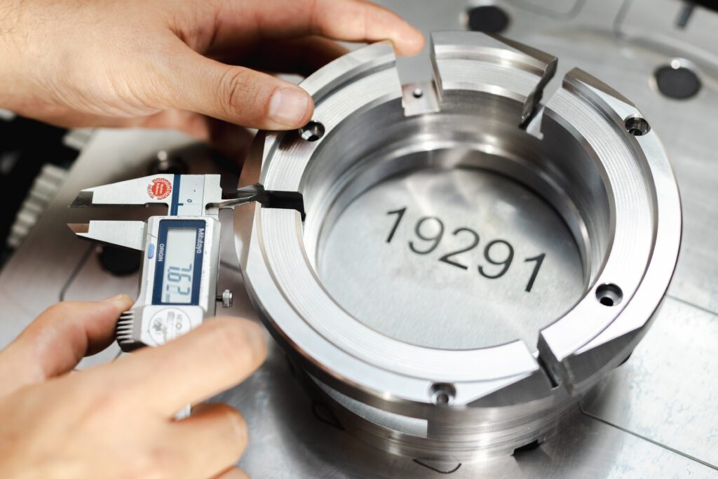 Präzisionsmessung eines metallischen Bauteils mit einer digitalen Schieblehre, sichtbare Gravur der Zahl 19291