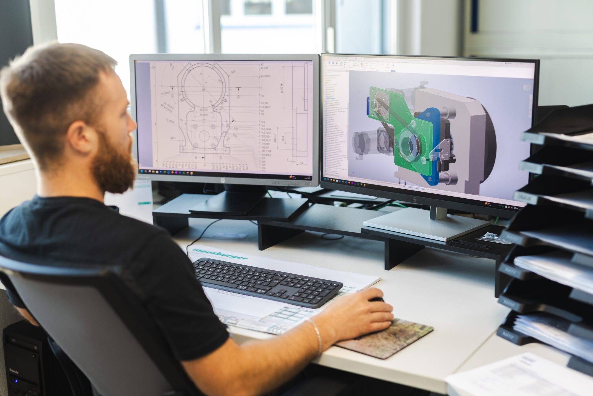 Mitarbeiter arbeitet am Computer mit CAD-Software auf zwei Monitoren