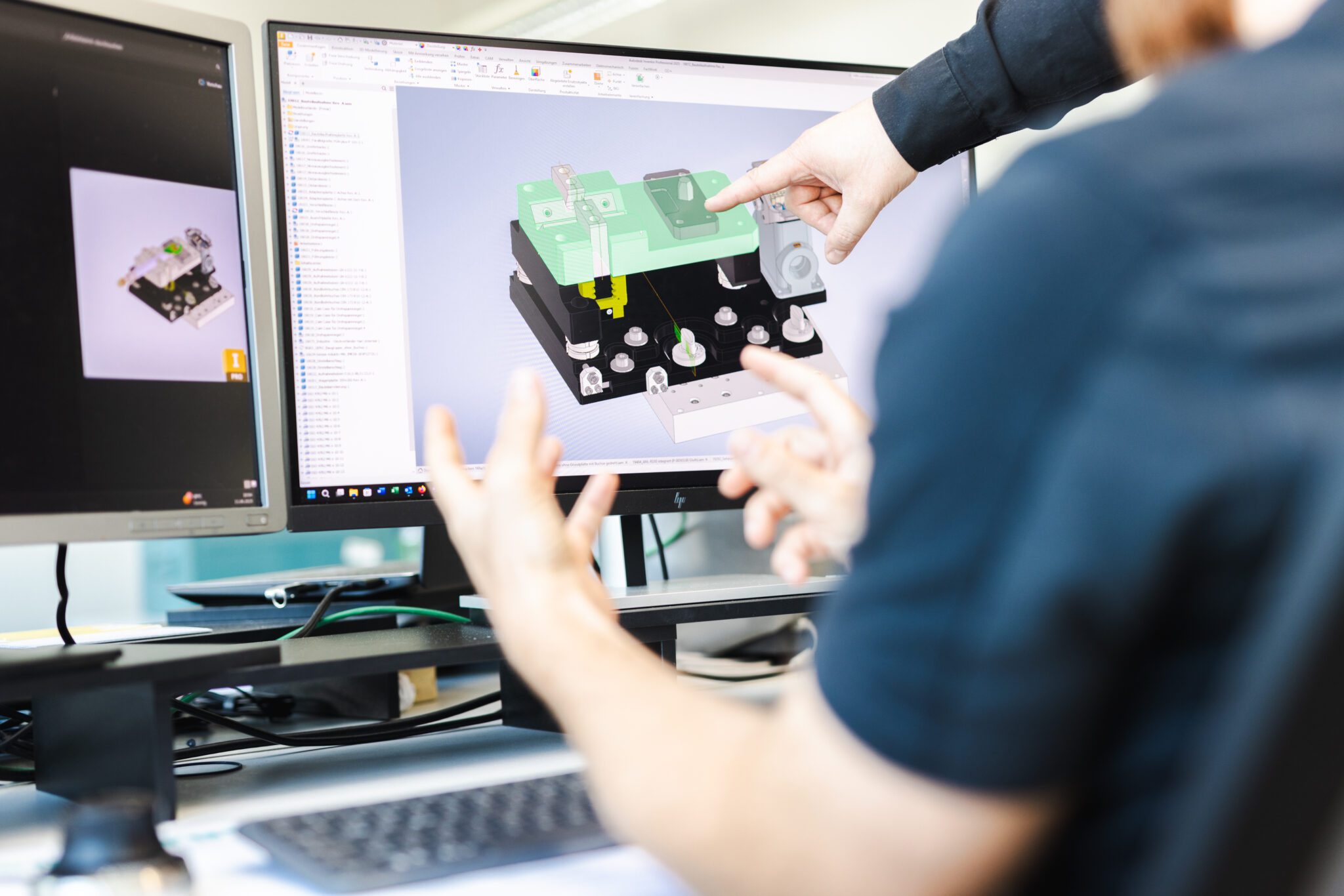 Teamarbeit am CAD-Arbeitsplatz: Zwei Mitarbeiter besprechen ein 3D-Modell einer Baugruppe am Bildschirm