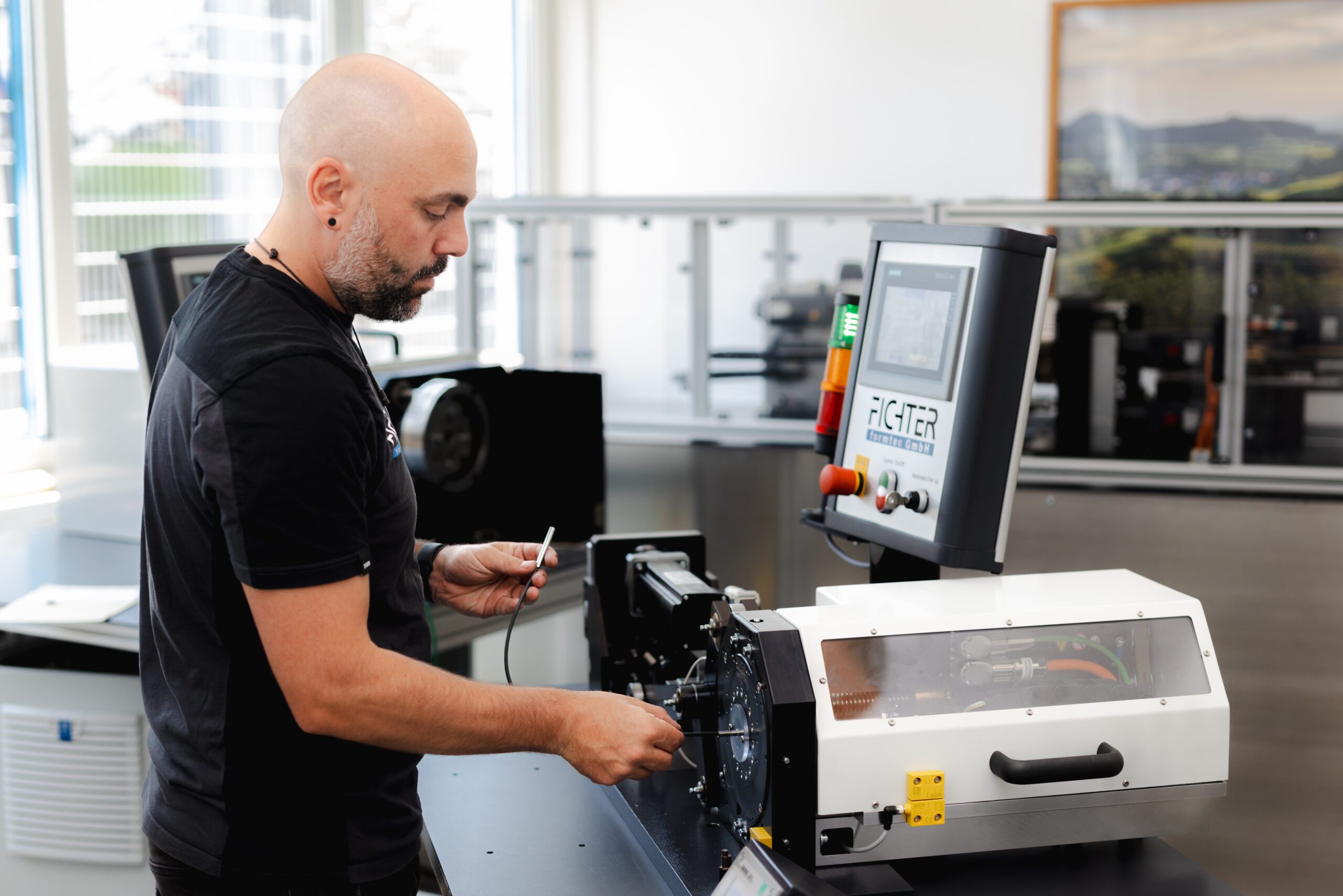 Mitarbeiter von Fichter formtec arbeitet an einer Maschine mit Bedienpanel im Produktionsbereich