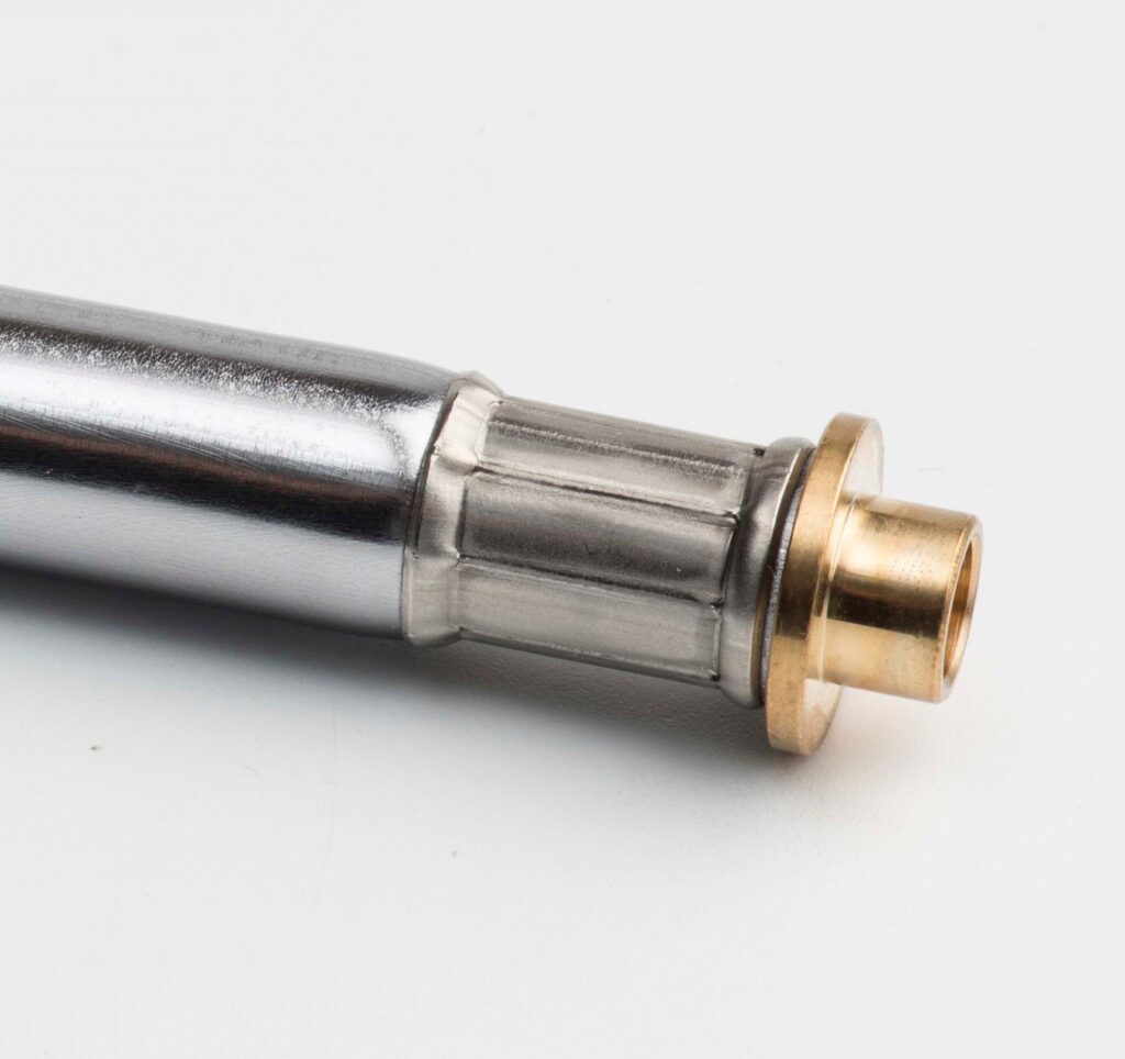 Nahaufnahme eines metallischen Präzisionsteils mit glänzender Oberfläche und goldfarbenem Anschlussstück, auf weißem Hintergrund fotografiert