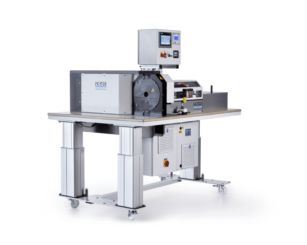 Industrielle Maschine von Fichter Formtec mit geschlossenem Gehäuse, montiert auf einem Metalltisch mit Rollen und integriertem Steuerdisplay